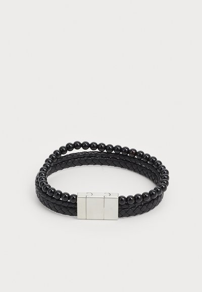 Bracelet en cuir tressé noir associé à des perles noires lisses, doté d'un fermoir en métal argenté, conçu dans un style à double brin.