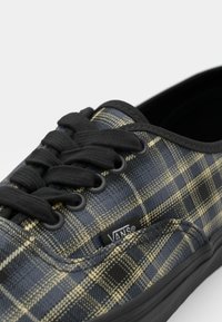 Black and yellow plaid Vans shoes featuring a canvas upper, rubber sole, round laces, and a label on the side.