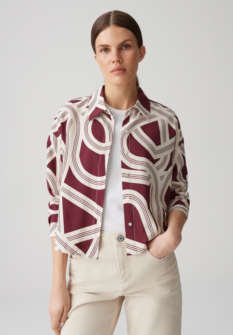 Camicia leggera con bottoni, caratterizzata da un motivo astratto in bordeaux e crema, design con colletto, maniche lunghe e vestibilità rilassata sopra una maglietta bianca.