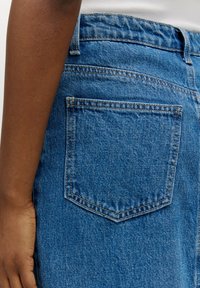 Denim jeans met een lichtblauwe wassing, voorzien van een enkele achterzak, zichtbare stiksels en een klassiek vijfzakdesign.