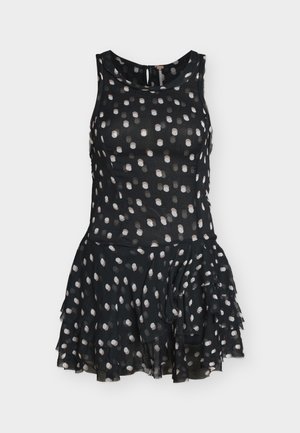 Ermeløs svart kjole med hvite polkadotter, tettsittende overdel, lagdelt volangskjørt og rund hals med knappelukking bak.