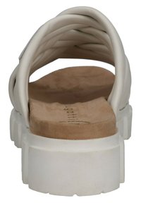 White sandal with a thick white sole, featuring a cushioned tan insole and a braided upper strap design. Smooth texture throughout.