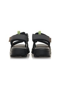 Sandali neri con cinturini grigi regolabili, un manico verde e suola nera texturizzata. Presentano una chiusura a fibbia sicura per un fit personalizzabile.