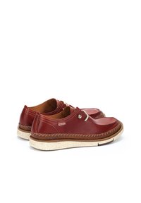 Chaussures en cuir rouge avec un bout arrondi, semelle blanche mouchetée et couture décorative. Comprend un œillet en métal et une étiquette de marque.