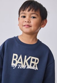 Marineblauwe sweatshirt gemaakt van een katoenmix, met een oversized pasvorm, ronde hals en crèmekleurige branding: "BAKER by Ted Baker" in vetgedrukte letters.