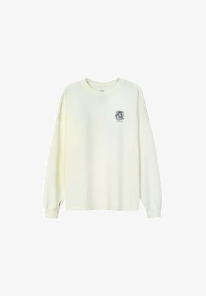 Ecru bluza z długim rękawem i okrągłym dekoltem, z małym czarno-czerwonym nadrukiem na lewej piersi oraz czerwoną przeszywką przy mankiecie.