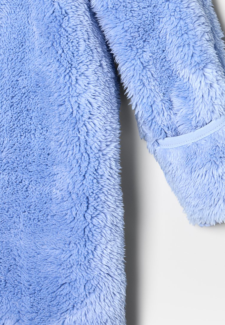 Prenda de forro polar azul suave y esponjosa con superficie texturizada; presenta un ribete liso de color azul claro en el puño.