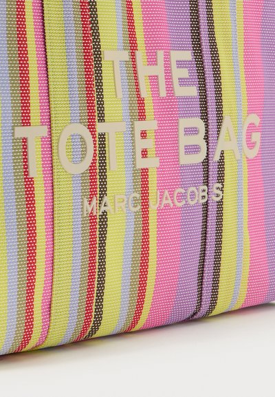 Sac cabas à rayures colorées avec des bandes jaunes, roses, violettes, rouges et vertes, marqué "THE TOTE BAG MARC JACOBS" en grandes lettres.