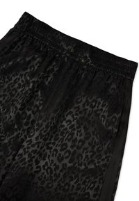 Spodnie dresowe w czarny panterkowy wzór z elastycznym pasem, o gładkiej fakturze i satynowym wykończeniu, ozdobione czarnymi bocznymi paskami.