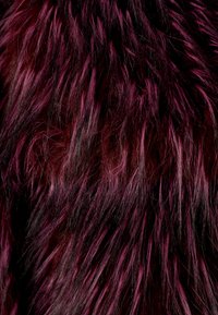 Tessuto in pelliccia finta in tonalità di rosso profondo e nero, caratterizzato da lunghe ciocche ondulate e morbide con texture variegate e sfumature di colore per una maggiore profondità.