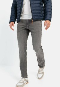 Gray denim jeans with a straight cut and minimal fading, paired with a white t-shirt and a navy puffer jacket, accentuated by light-colored sneakers.