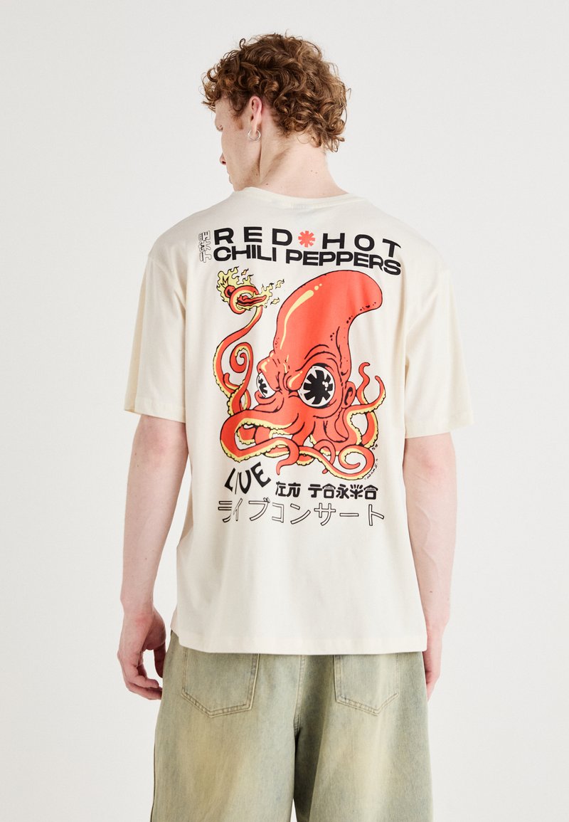 Cremefarvet oversized t-shirt med en illustration af en blæksprutte og teksten "RED HOT CHILI PEPPERS" i fed sort og rød.