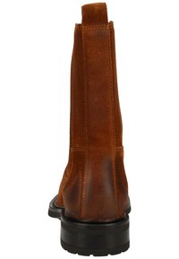 Bottines en suède marron avec une texture lisse, bout rond et semelle en caoutchouc ; inclut une languette à l'arrière pour un enfilage facile.