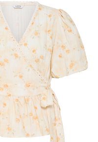 Blouse cache-cœur crème avec manches courtes bouffantes, petit imprimé de roses orange, bordure festonnée et ceinture en tissu à la taille.