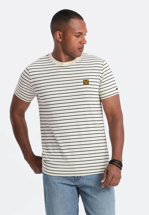 T-shirt à col rond rayé en crème avec des rayures noires, présentant un petit patch logo jaune sur la poitrine. Manches courtes et coupe régulière.
