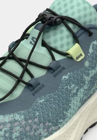 Ελαφρύ αθλητικό παπούτσι με υφασμάτινο, μέντα-πράσινο επάνω μέρος, σκοτεινά κορδόνια και μοτίβο στη σόλα. Διαθέτει υποστηρικτικές επικαλύψεις και ανθεκτικό φινίρισμα.