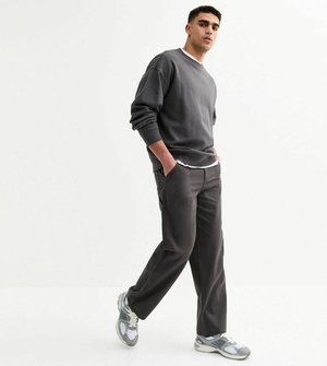 Grå sweatshirt med rund hals, kombinerad med mörkgrå cargobyxor. Modellen bär texturerade sneakers och står framför en neutral bakgrund.