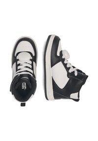 Čierno-biele vysoké tenisky s bielymi šnúrkami a guľatým bielym sensorom pripevneným na jazyku na bielom pozadí.