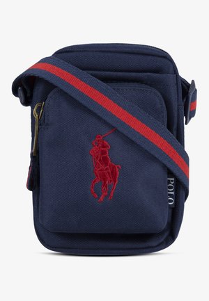 Μικρή ναυτική τσάντα χιαστί με κόκκινο κεντημένο παίκτη πόλο, μπροστινή τσέπη με φερμουάρ και ναυτική λουρίδα με κόκκινη ρίγα.