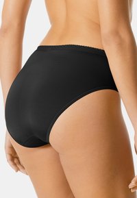 Svarta högmidjade trosor gjorda av smidigt tyg. Har en delikat scalloped midjeband och en sömlös finish för komfort.
