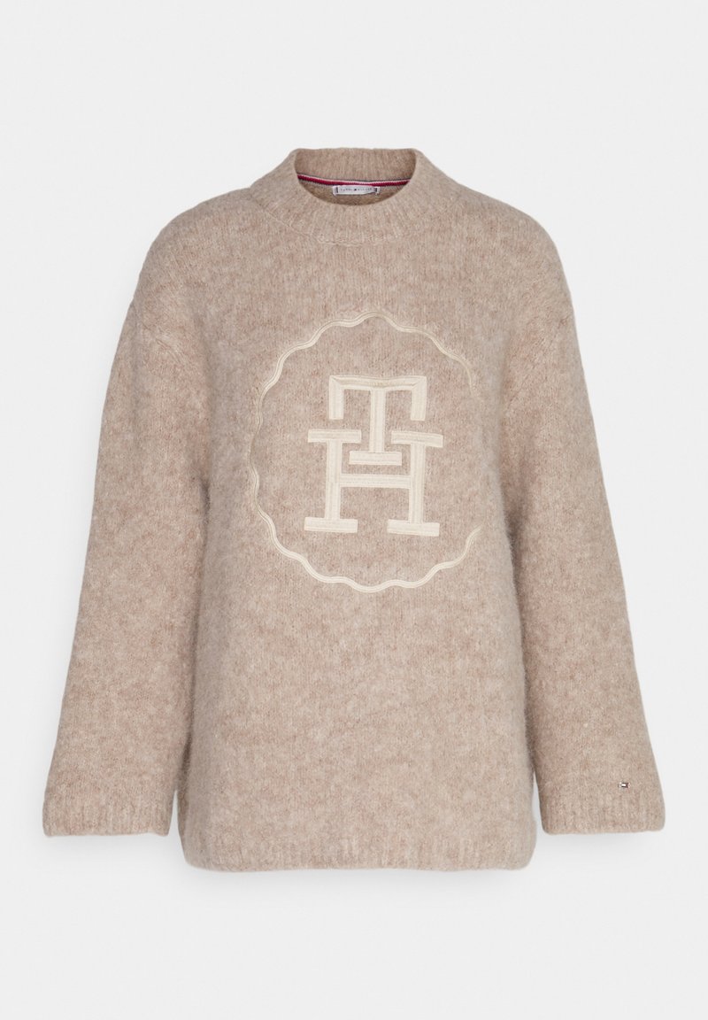 Pull en maille beige doux avec col rond côtelé, manches longues et logo embossé "TH" entrelacé centré sur le devant.