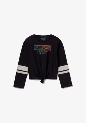 Camiseta negra de manga larga y corte corto con el logo de "STRANGER THINGS" en texto colorido, con detalles de rayas grises en las mangas y dobladillo anudado.