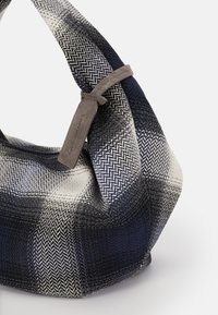Tasche mit Hahnentritt-Muster in Marineblau, Schwarz und Weiß aus einem weichen Stoff. Verfügt über einen kurzen grauen Lederhenkel. Einzigartige runde Form.
