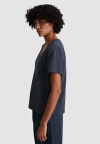 Dark navy cotton t-shirt with a V-neck and short sleeves, featuring a relaxed fit and soft texture, shown from the side.