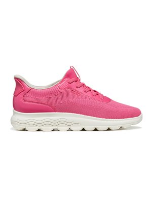 Zapatilla deportiva de color rosa brillante con suela blanca con patrón ondulado y parte superior de malla, vista desde un lado sobre un fondo blanco.