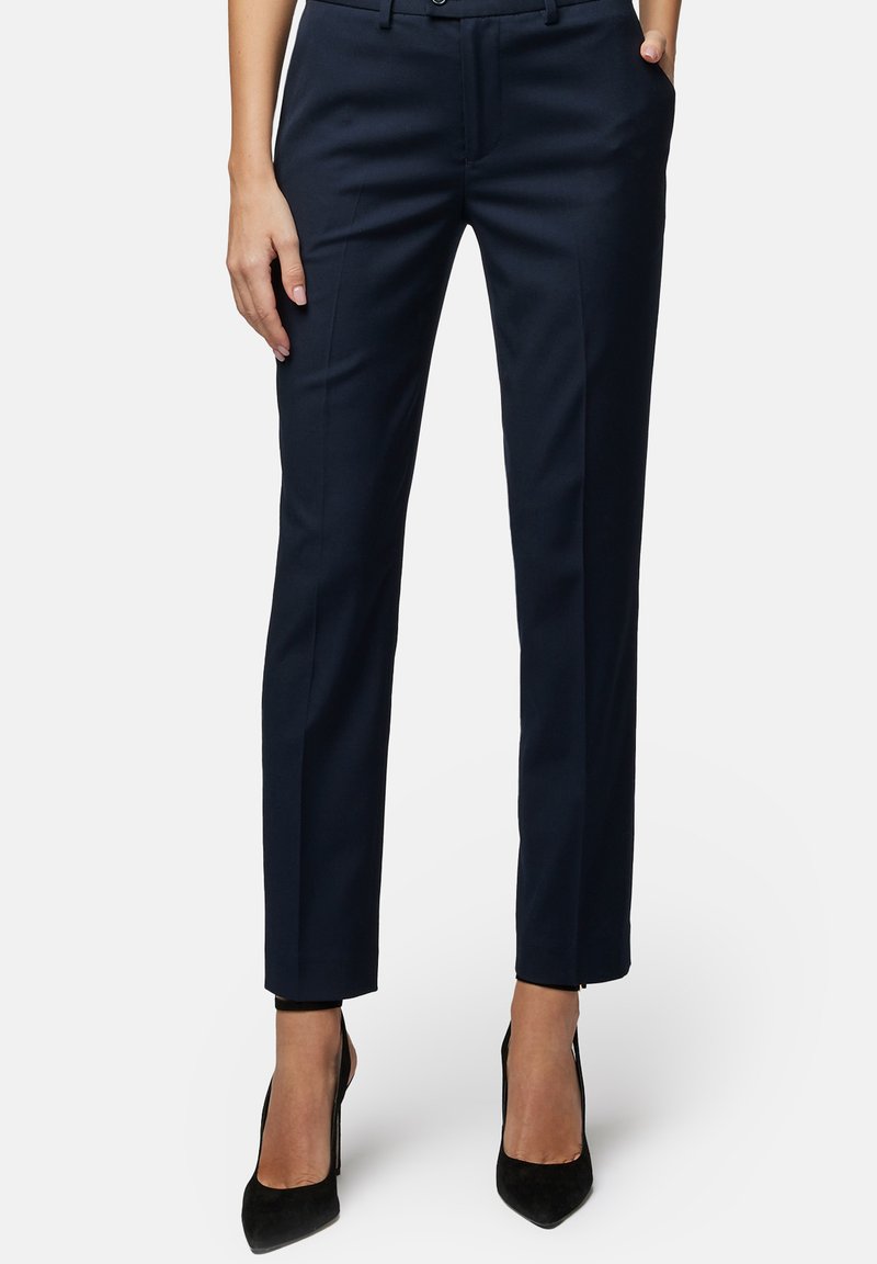 Granatowe spodnie o prostym kroju, z kieszeniami z przodu, szlufkami na pasek i gładką fakturą, w komplecie z czarnymi szpilkami.