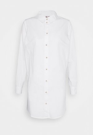 Chemise blanche en coton, avec col, manches longues et coupe droite, dotée de sept boutons visibles sur le devant.