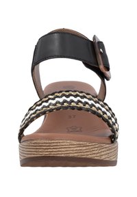 Black leather strap sandal with braided black, white, and tan woven band. Features a cushioned brown footbed and wood-grain textured sole.
