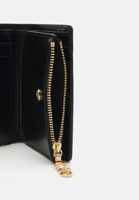 Black leather wallet with gold zipper detailing, featuring multiple card slots and a coin pocket. Interior has a smooth textured finish.