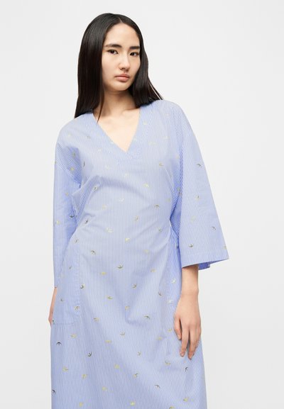 Μπλε ριγωτό φόρεμα με κίτρινα και μαύρα φύλλα, ντεκολτέ σε σχήμα V, και φαρδιά μανίκια. Κατασκευασμένο από ελαφρύ ύφασμα με άνετη γραμμή.