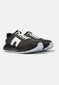 Scarpe sportive in bianco e nero con una tomaia in tessuto testurizzato, punta rotonda, lacci bianchi e una suola grigia spessa con battistrada circolare.