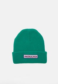 Bonnet en tricot vert avec un revers et un logo en patch. La texture est côtelée, avec une structure douce et près du corps.