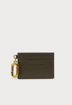 Tamsiai alyvuogių spalvos Marc Jacobs kortelių laikiklis su trim kortelių lizdais ir auksinio atspalvio ovaliu raktų pakabuku pritvirtintu kairėje pusėje.
