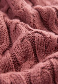 Kabelstickad tröja i färgen dammig ros, med texturerade, vävda mönster som skapar ett mjukt, mysigt utseende med en lätt fluffighet.
