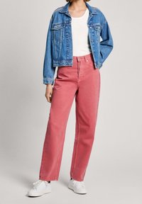 Niebieska kurtka dżinsowa, biała koszulka i różowe dżinsy o szerokich nogawkach z wysokim stanem. Białe sneakersy dopełniają stylizację.