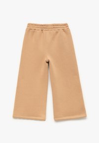 Pantalones de pierna ancha beige, fabricados en un material suave con una cinturilla elástica, que cuentan con una textura lisa y un acabado de dobladillo limpio.
