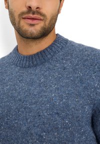 Maglione lavorato a maglia di colore blu scuro con un motivo testurizzato, caratterizzato da un collo rotondo a coste e delle macchie di bianco e blu chiaro disperse in tutto il tessuto.