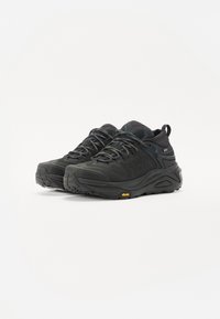 Chaussures de randonnée noires avec un design texturé, présentant un collier rembourré, un système de laçage proéminent et une semelle extérieure en caoutchouc Vibram distincte pour une meilleure adhérence.