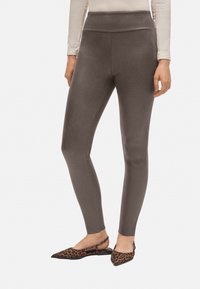 Leggings de tiro alto y ajustados en un suave tejido gris oscuro. Presentan una textura lisa y una silueta estilizada, combinados con zapatos planos de leopardo con punta.