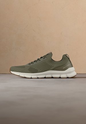 Olivengroene gebreide sneaker met witte segmenten zool, veters en treklus, met Marc O’Polo merk op het hielpaneel.