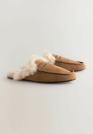 Papuci din suede maro cu căptușeală din blană sintetică, design slip-on și detalii cusute pe partea superioară. Sole din cauciuc negru pentru aderență.