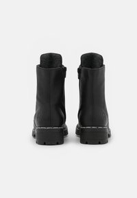 Bottes de cheville en cuir noir avec une semelle en caoutchouc texturée, fermeture éclair et doublure intérieure. Présente un logo subtil sur le côté.