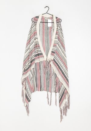 Poncho tricoté à rayures rose, noir et blanc, avec un col en V et des franges, suspendu à un cintre noir.