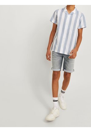 Korte mouw blouse met blauw-witte verticale strepen, gecombineerd met opgerolde denim shorts en witte sneakers.