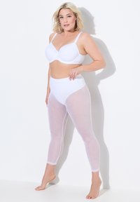Soutien-gorge blanc avec coques moulées et bretelles réglables, associé à un legging en maille blanc taille haute avec un motif en losanges et une ceinture solide.