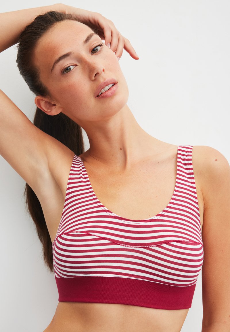 Rood-wit gestreepte bralette met een ronde halslijn en brede bandjes. Heeft een effen rode band aan de onderkant. Zachte stoftextuur.